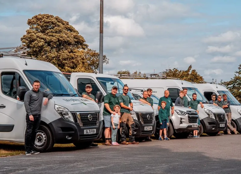 The full Stephen Paul Gardens workforce standing alongside their line-up of branded company vans and trucks.