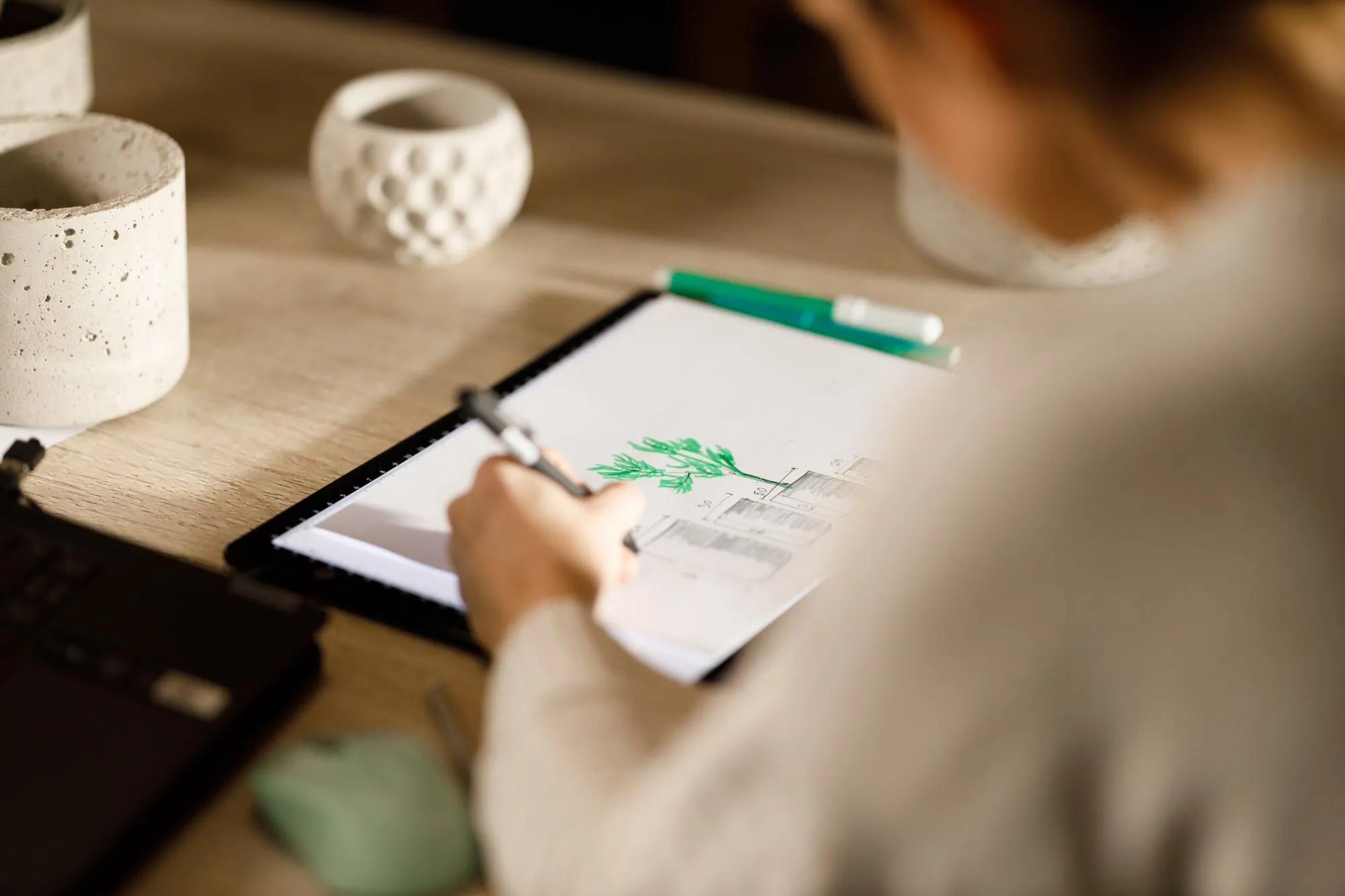 A landscape designer sketching a detailed garden planting plan on a digital tablet using a stylus.