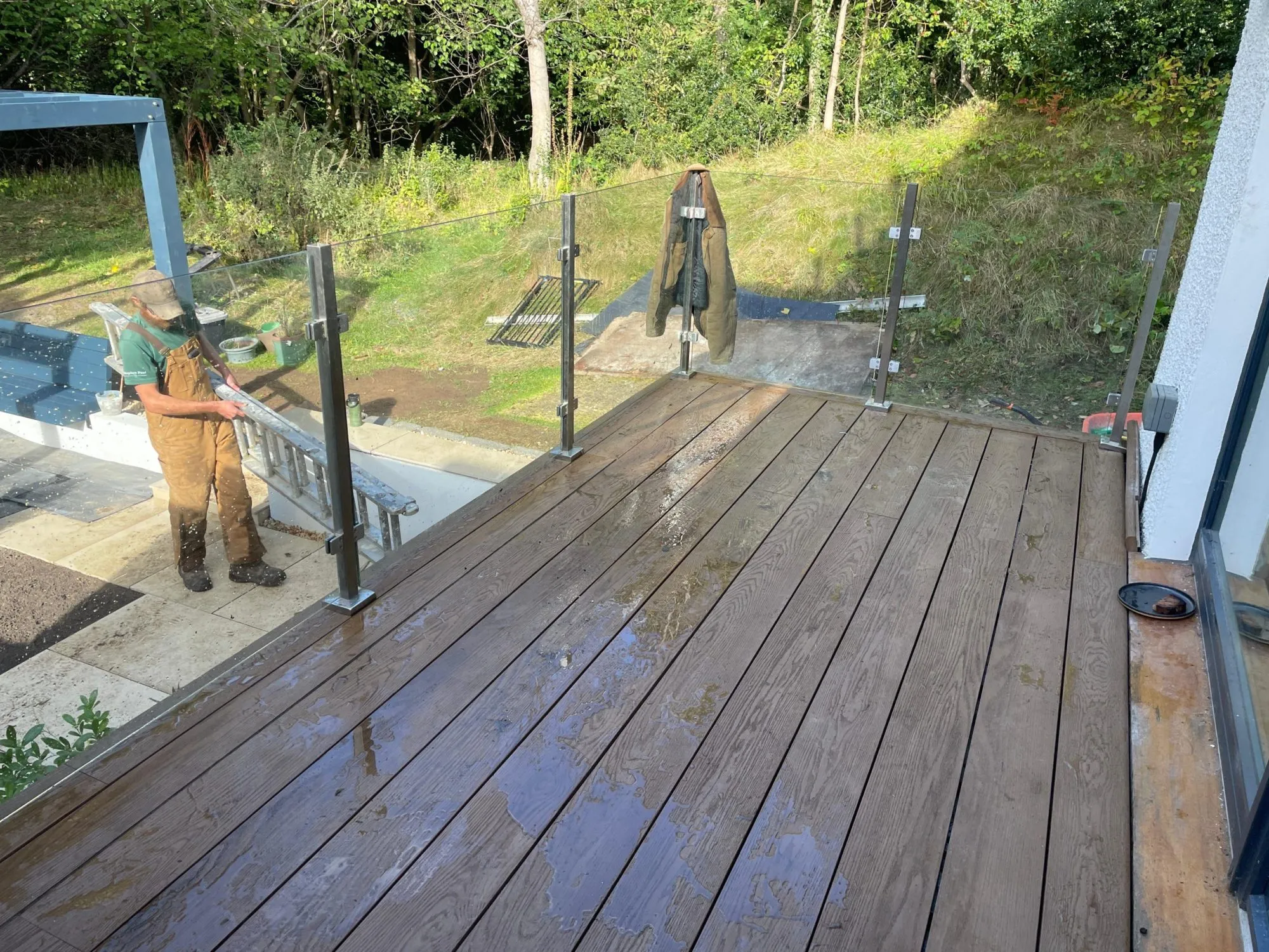 A Stephen Paul Gardens team member installing glass balustrades on a new composite decking balcony.