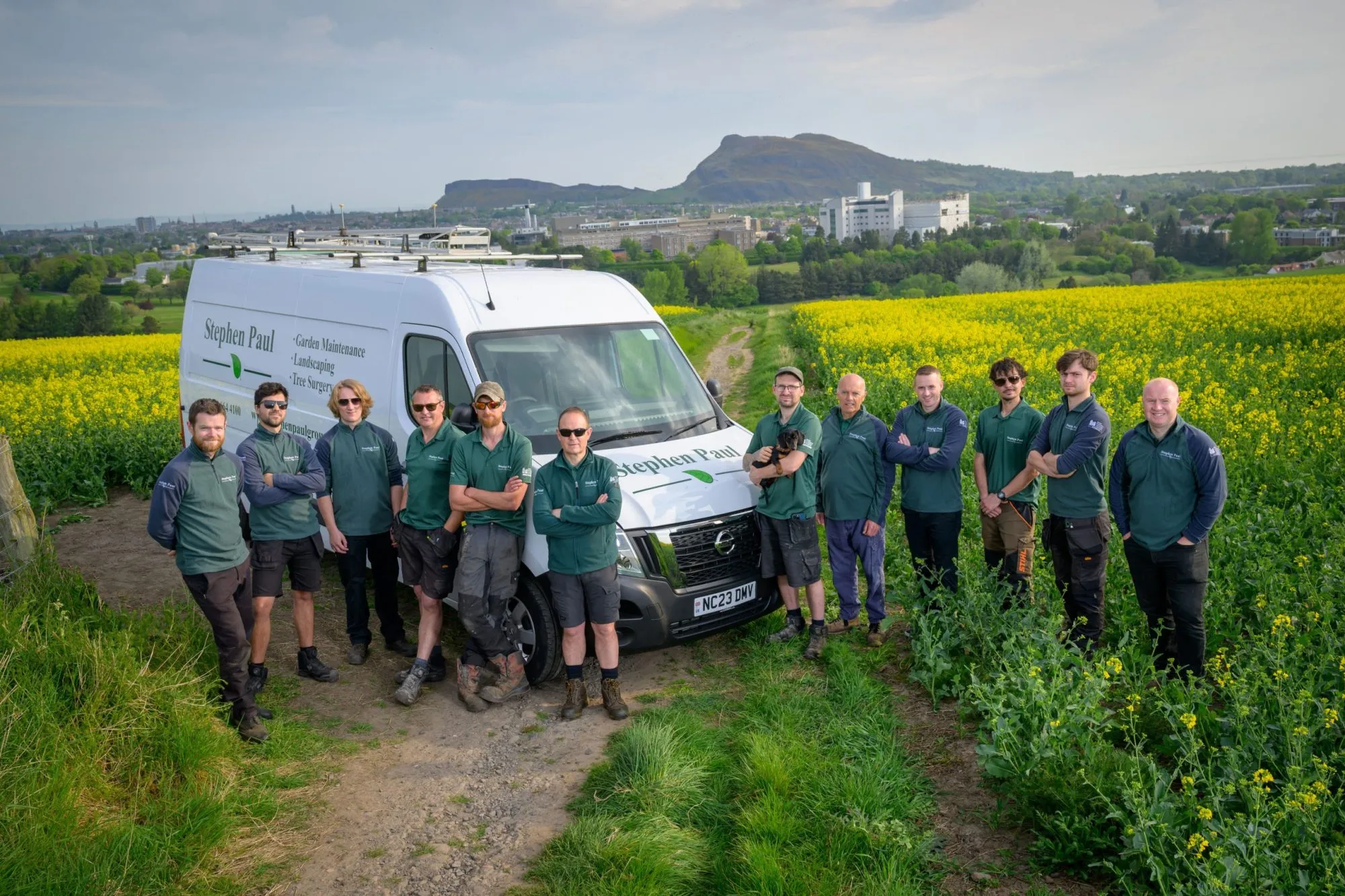 The Stephen Paul Gardens team standing together beside a company van in front of a scenic Edinburgh backdrop.