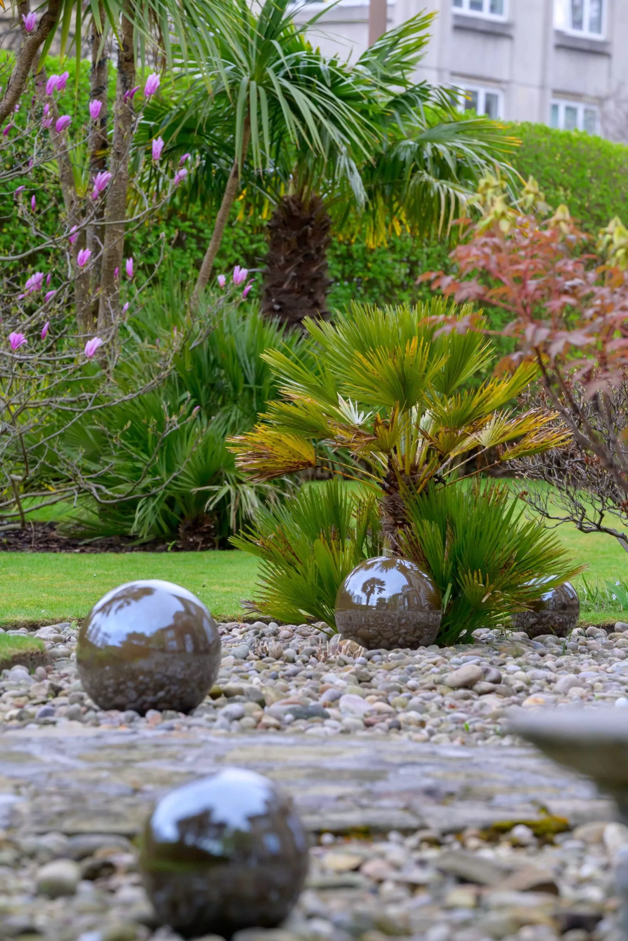 Photo of polished stone sphere water features nestled in a decorative gravel garden bed by Stephen Paul Gardens.